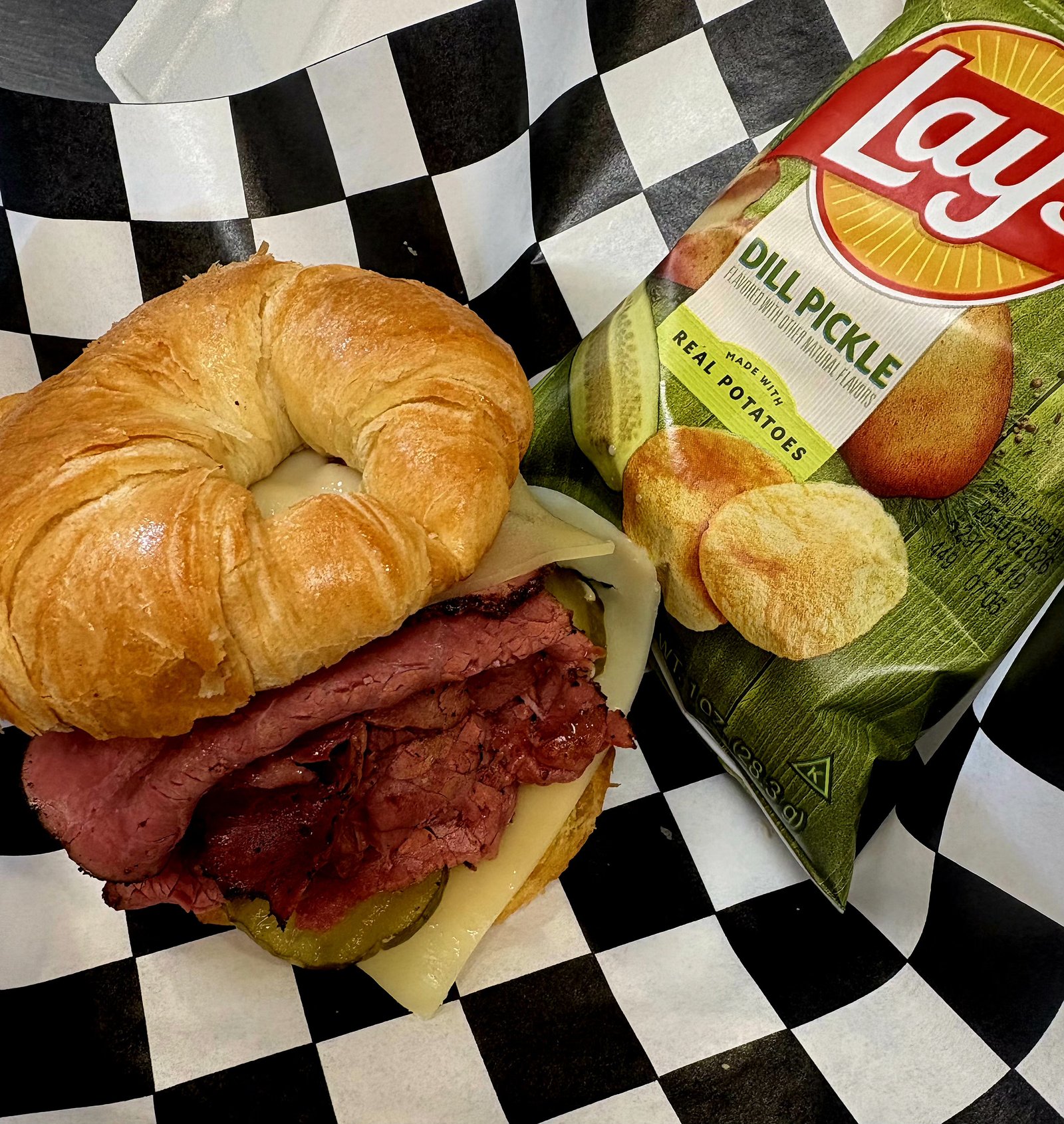 Pastrami melt on a croissant with dill pickle chips
